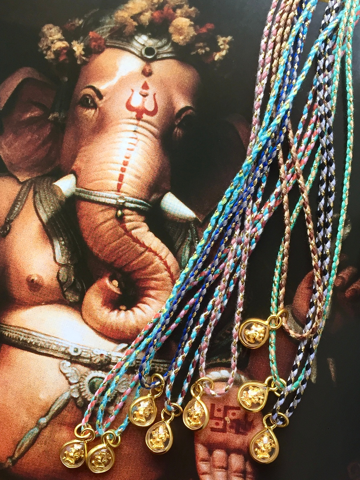 ganesh amulet magic cord necklace with a drop-shaped pendant holding a tiny golden murti of ganesh on a colorful golden cord