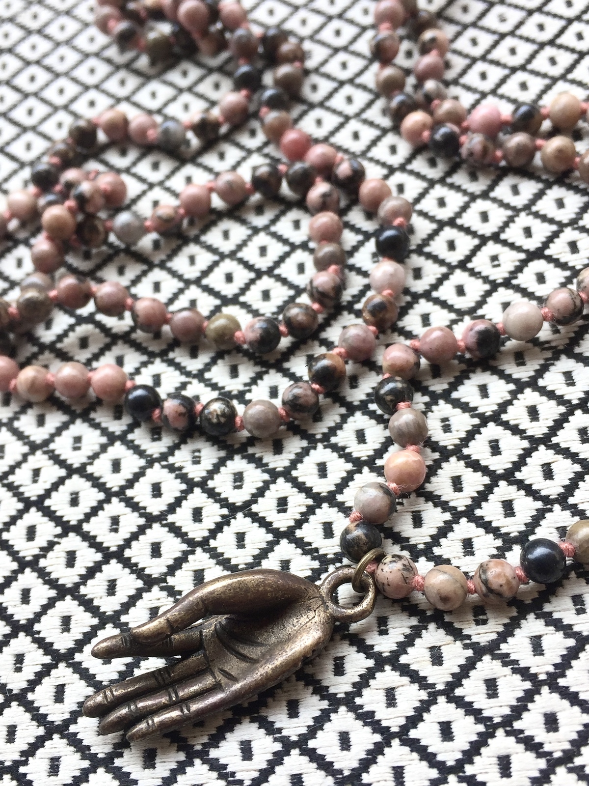 bronze buddha mudra necklace with 4mm round rhodonite stone beads and hand-carved bronze brass pendant depicting buddha hand in gyan mudra, symbolizing knowledge, wisdom, and mindfulness