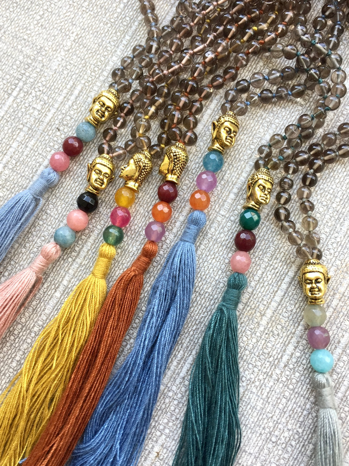 handcrafted smoky quartz necklace with 4mm round beads, colorful tassel, tiny golden buddha head, and three agate guru beads matching the tassel’s colors