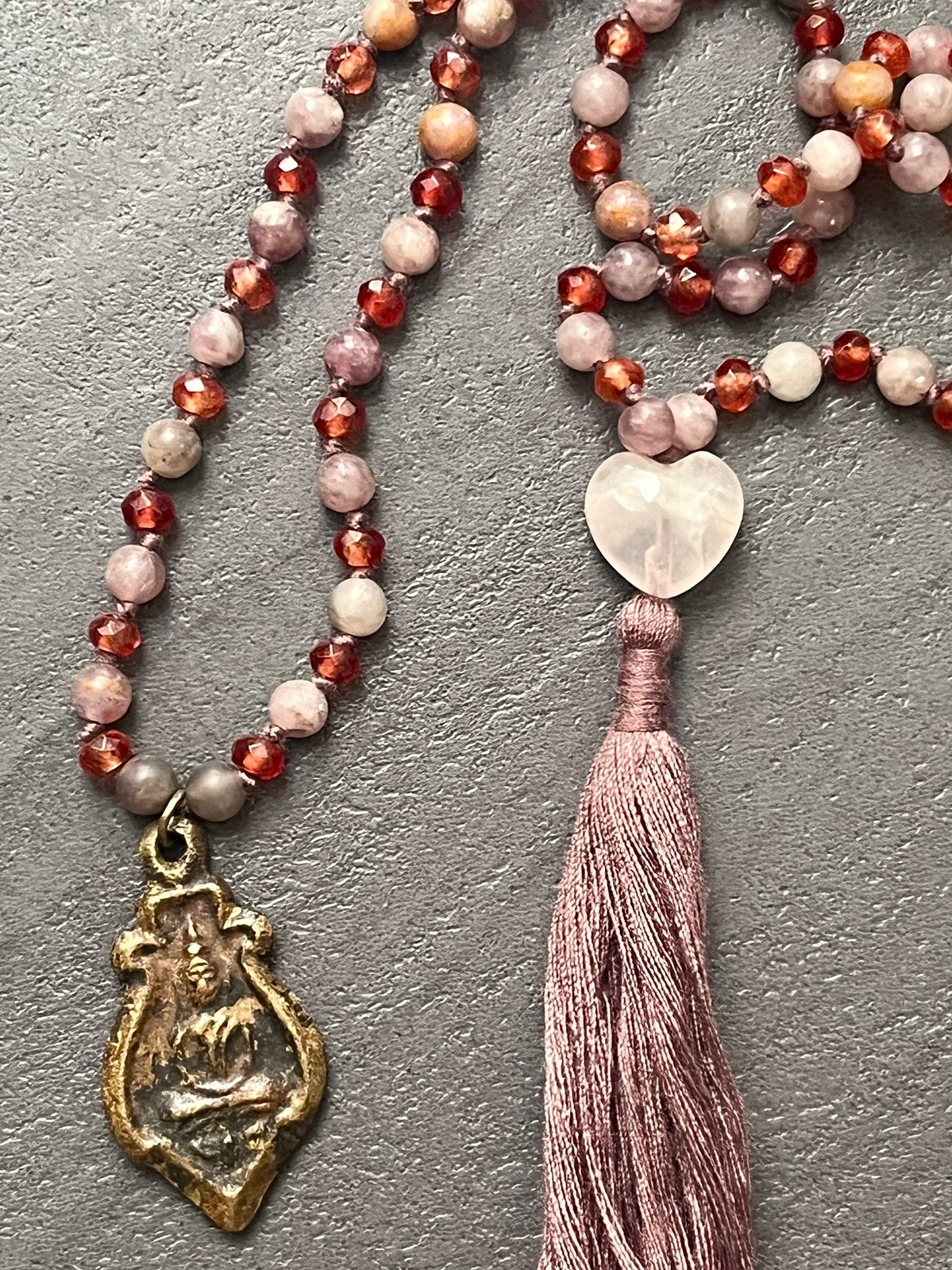 buddha bliss double mala necklace made of hand-knotted faceted orange agate and round quartzite beads with a rose quartz heart guru bead and brass buddha pendant, symbolizing joy, love, and serenity