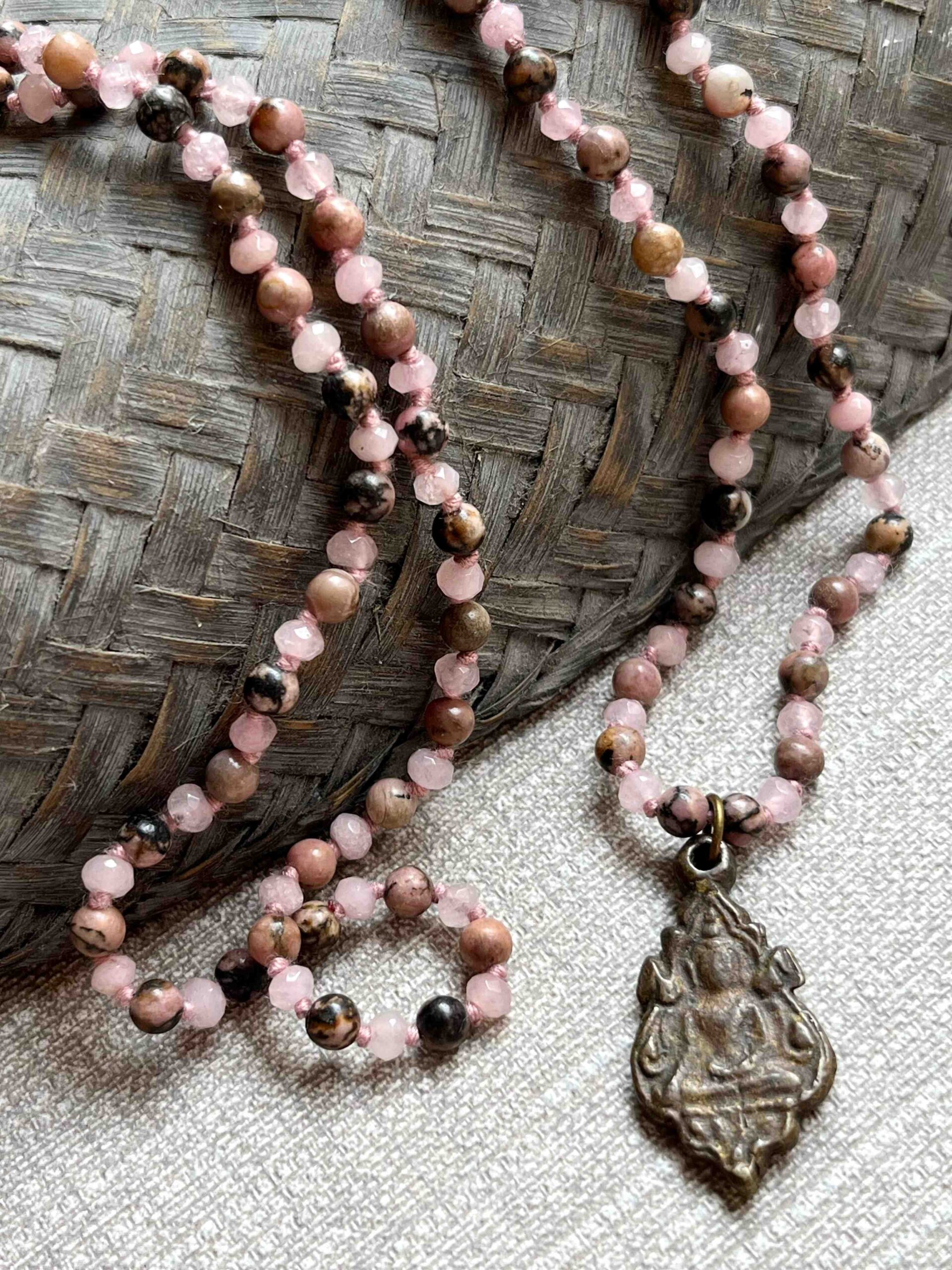 hand-knotted buddha inner beauty necklace featuring a buddhist amulet from a temple in thailand, with alternating flat faceted rose quartz and round rhodonite beads symbolizing love, compassion, forgiveness, and balance