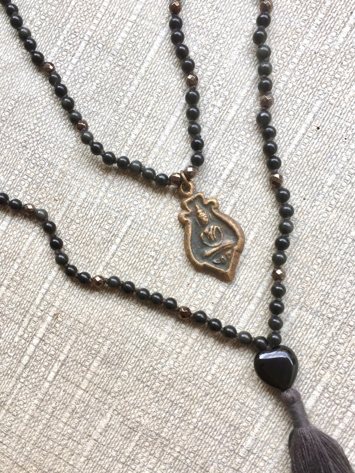 buddha shimmer double mala handcrafted with dark grey obsidian and faceted bronze hematite beads, featuring a black onyx heart guru bead, tassel, and antique bronze thai buddha amulet for protection and grounding energy