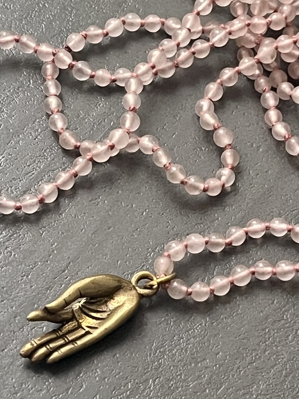 golden buddha mudra necklace with 4mm round rose quartz stone beads and hand-carved bronze brass pendant depicting buddha hand in gyan mudra, symbolizing knowledge, wisdom, and mindfulness
