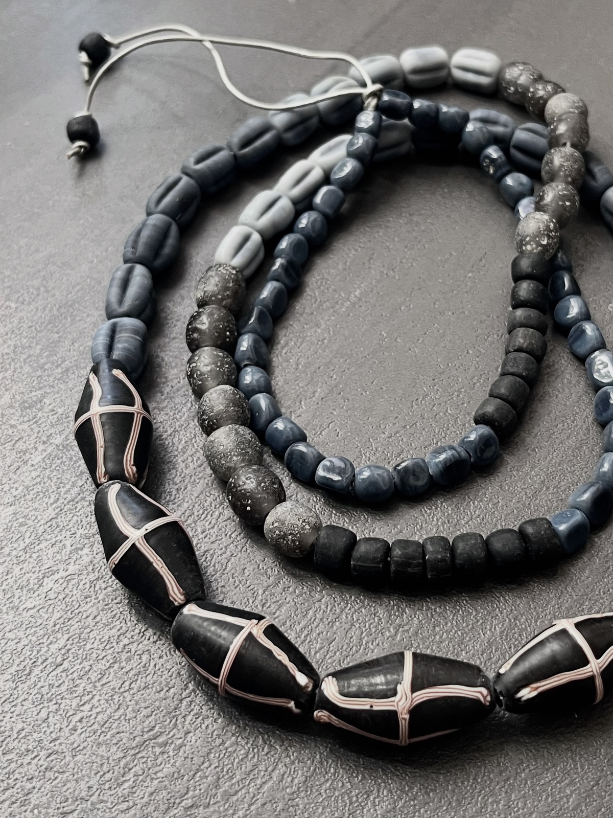 java necklace with black and grey handmade javanese glass beads in different shapes on a leather strap inspired by indonesian textiles
