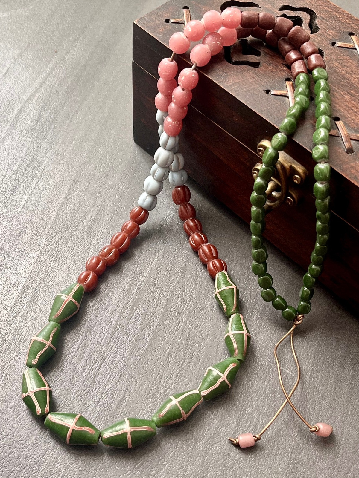 java necklace with forest green, pink and brown handmade javanese glass beads in different shapes on a leather strap inspired by indonesian textiles