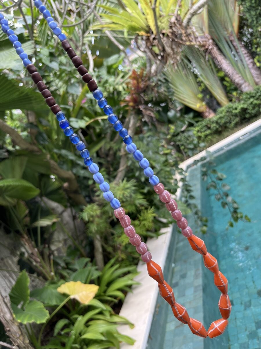 java necklace with orange, blue, and pink handmade javanese glass beads in different shapes on a leather strap inspired by indonesian textiles