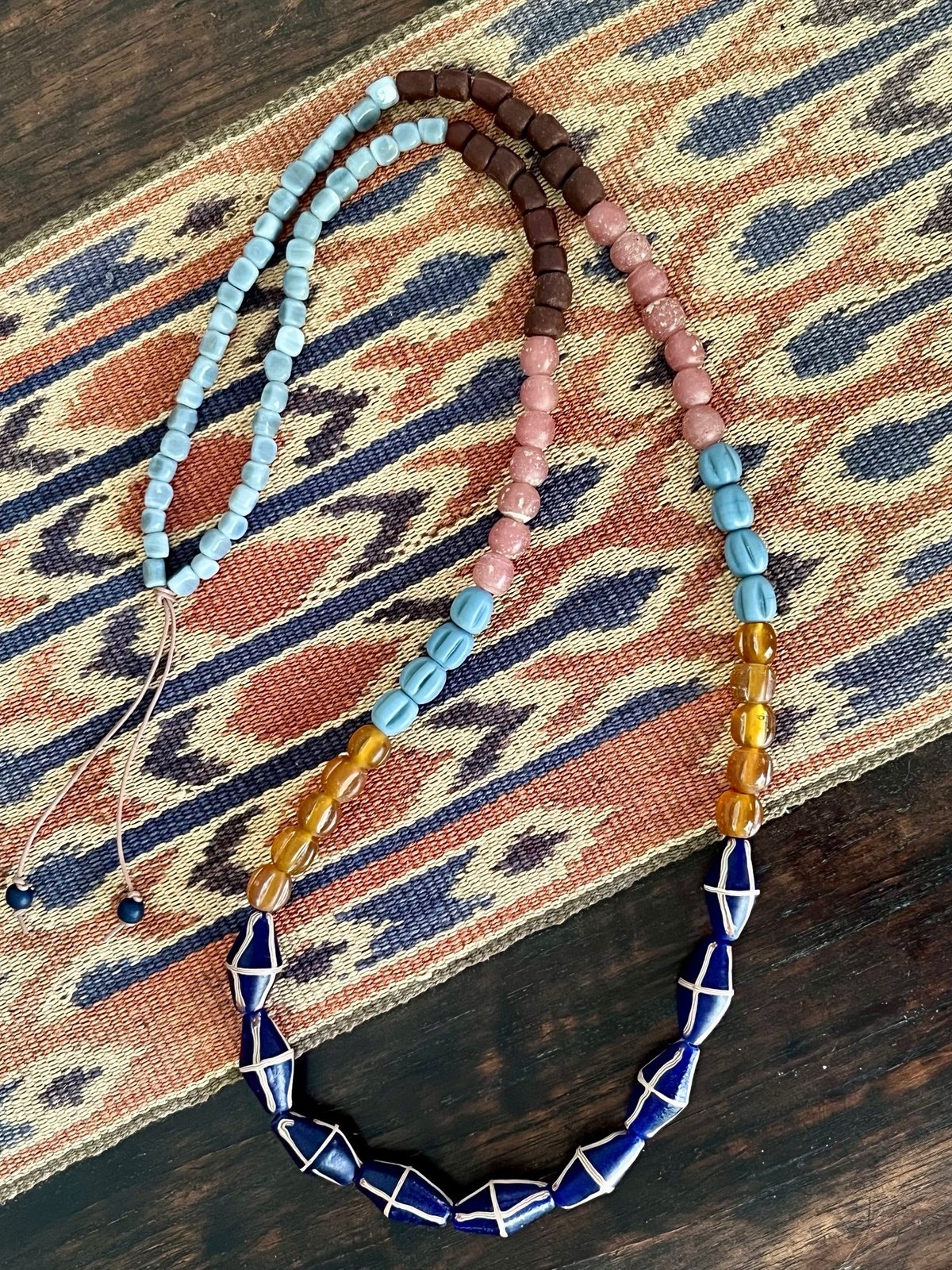 java necklace with royal blue, pink and grey handmade javanese glass beads in different shapes on a leather strap inspired by indonesian textiles