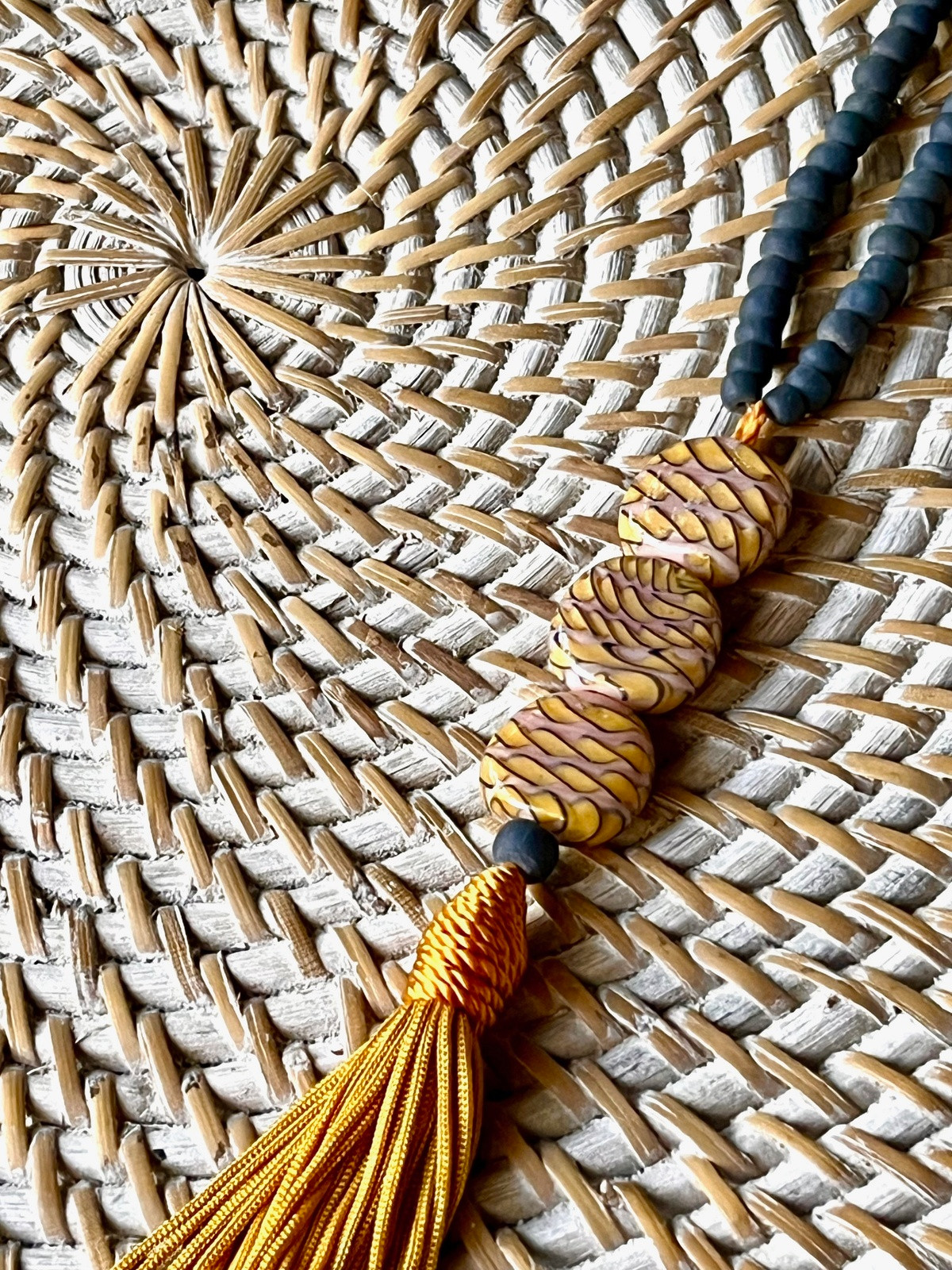 sarong necklace inspired by balinese sarongs, handmade with grey javanese matte glass beads, three glossy multicolor beads, and a matching viscose yellow tassel