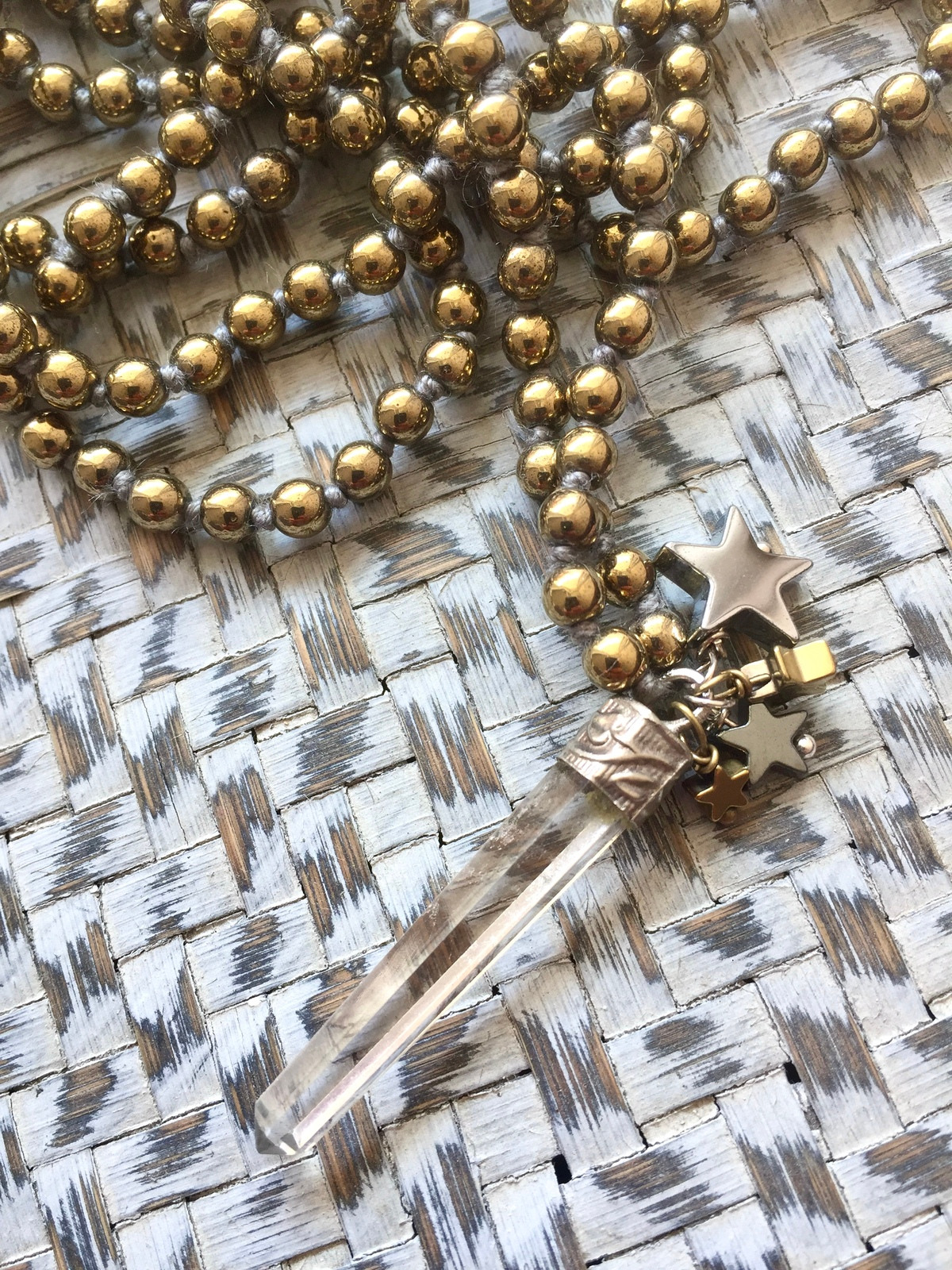 stars sparkle necklace made with hand-knotted 4mm golden hematite beads and a rock crystal pendant with golden sparkles, decorated with four hematite stars in silver, gold, and gunmetal