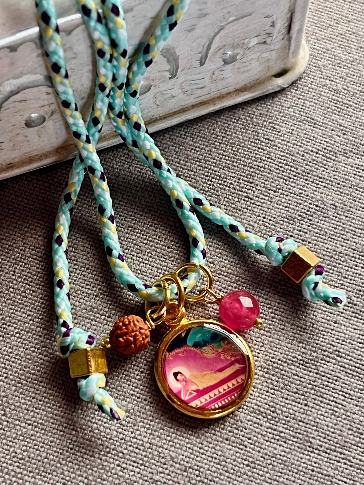 colorful necklace with adjustable aqua pop cord, vintage golden pendant featuring buddha in meditative poses, rudraksha seed, and agate bead — a vibrant blend of spirituality, mindfulness, and modern style