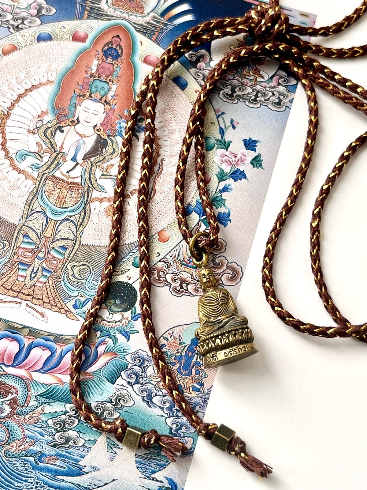 necklace with brown golden lurex cotton cord and thai brass amulet depicting the buddha in stillness, symbolizing peace, protection, and spiritual guidance