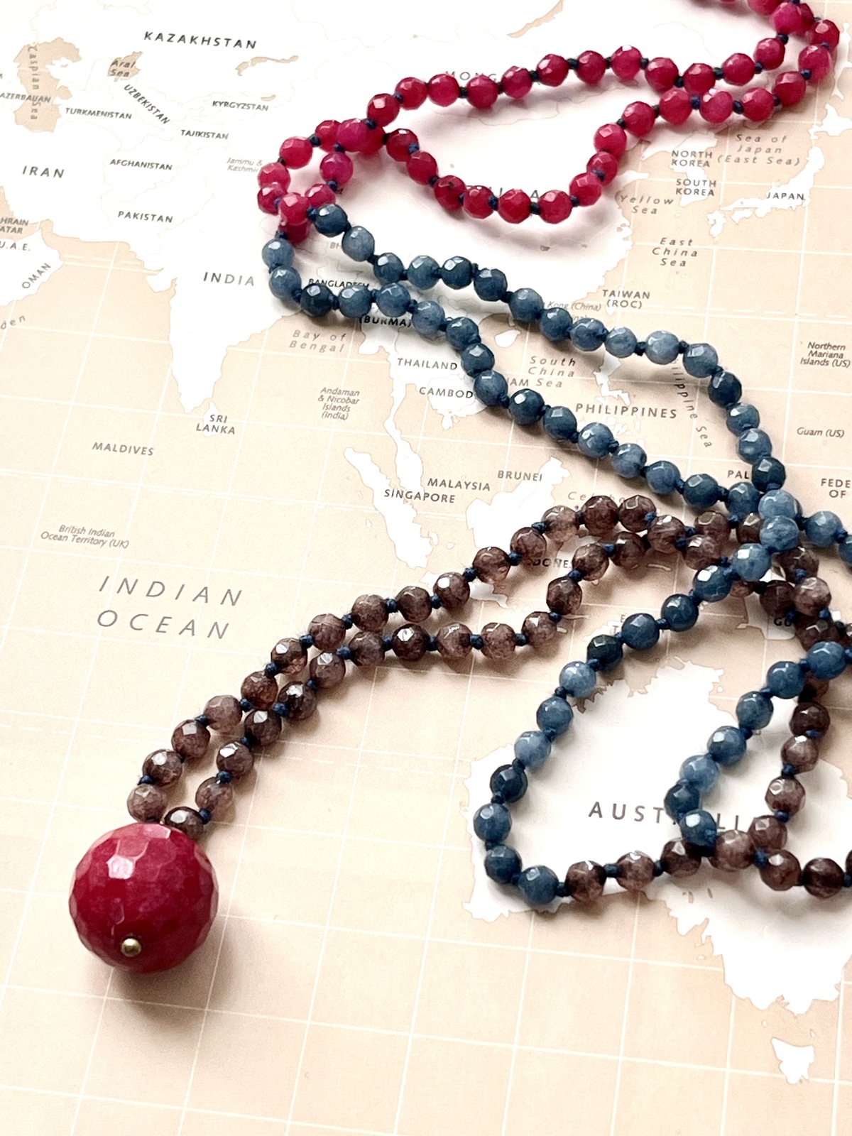 globe necklace with hand-knotted brown blue ruby agate beads and a round faceted stone pendant symbolizing the globe, featuring a chic minimal design