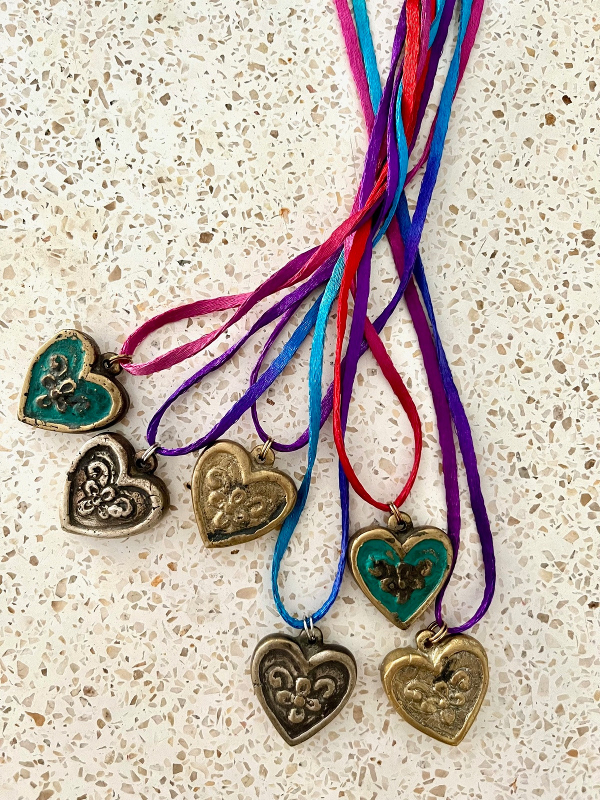 necklace with rainbow-colored indian mouli cord and brass heart pendant in gold or bronze finish, symbolizing love, loyalty, protection, and devotion