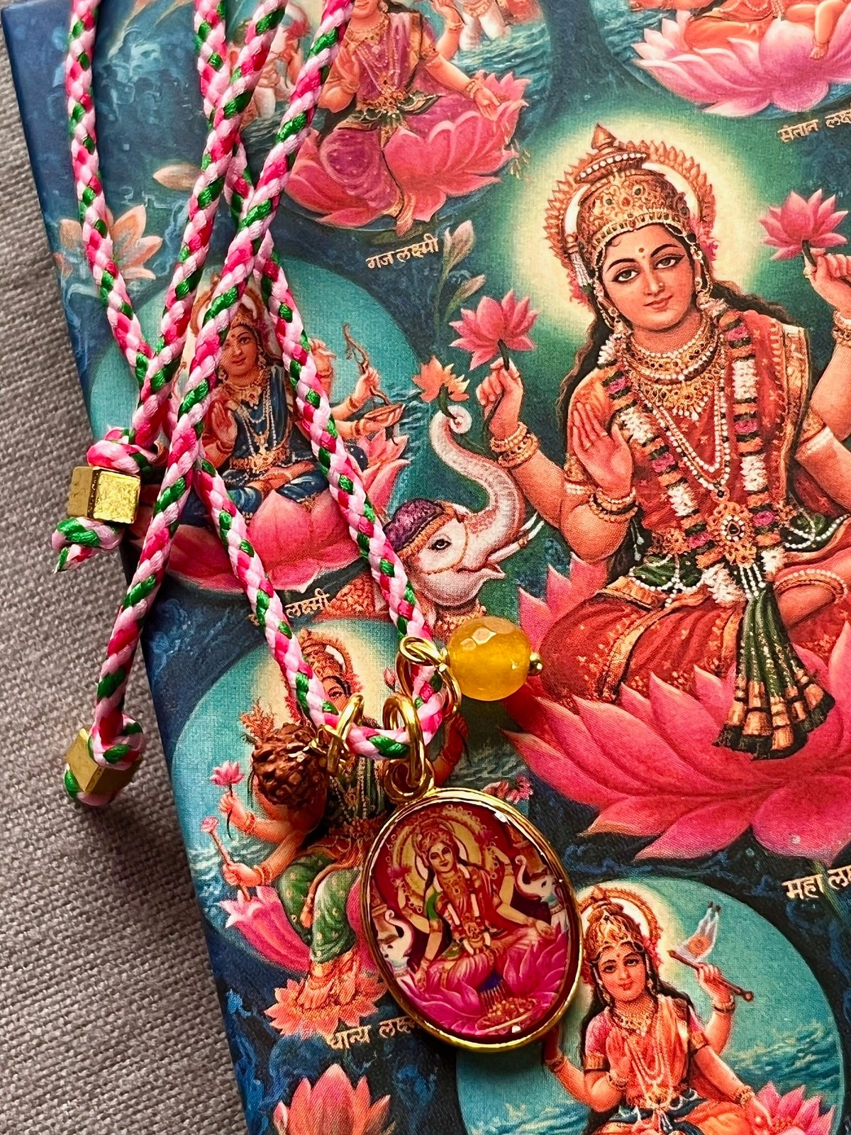 colorful laxmi funky cord necklace with adjustable pink pop cord, vintage golden pendant of goddess laxmi, rudraksha seed, and agate bead, a vibrant accessory symbolizing abundance, prosperity, and wealth