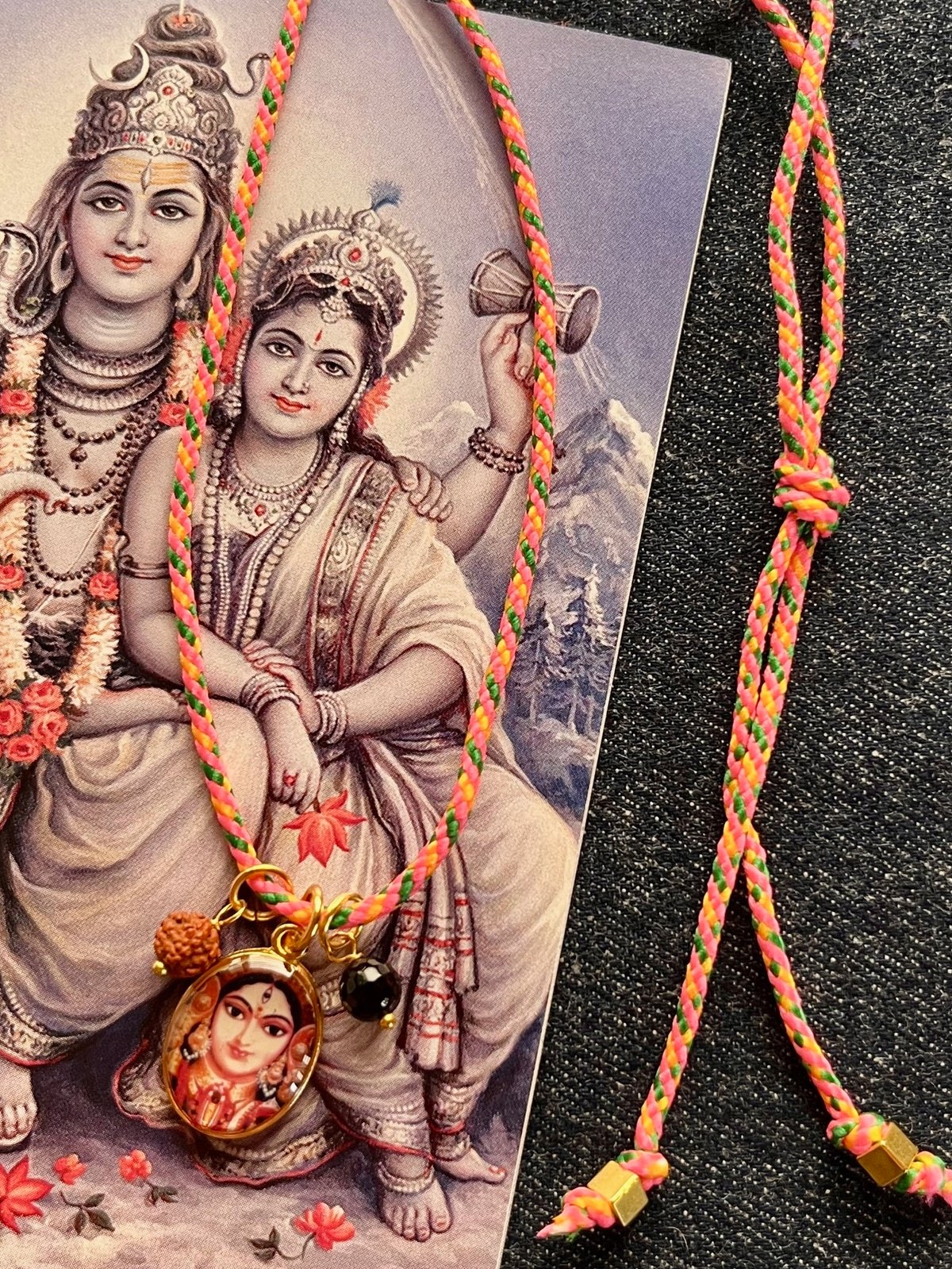 colorful parvati funky cord necklace with adjustable salmon pop cord, vintage golden pendant of goddess durga, rudraksha seed, and agate bead, a vibrant accessory symbolizing devotion, love, and feminine energy